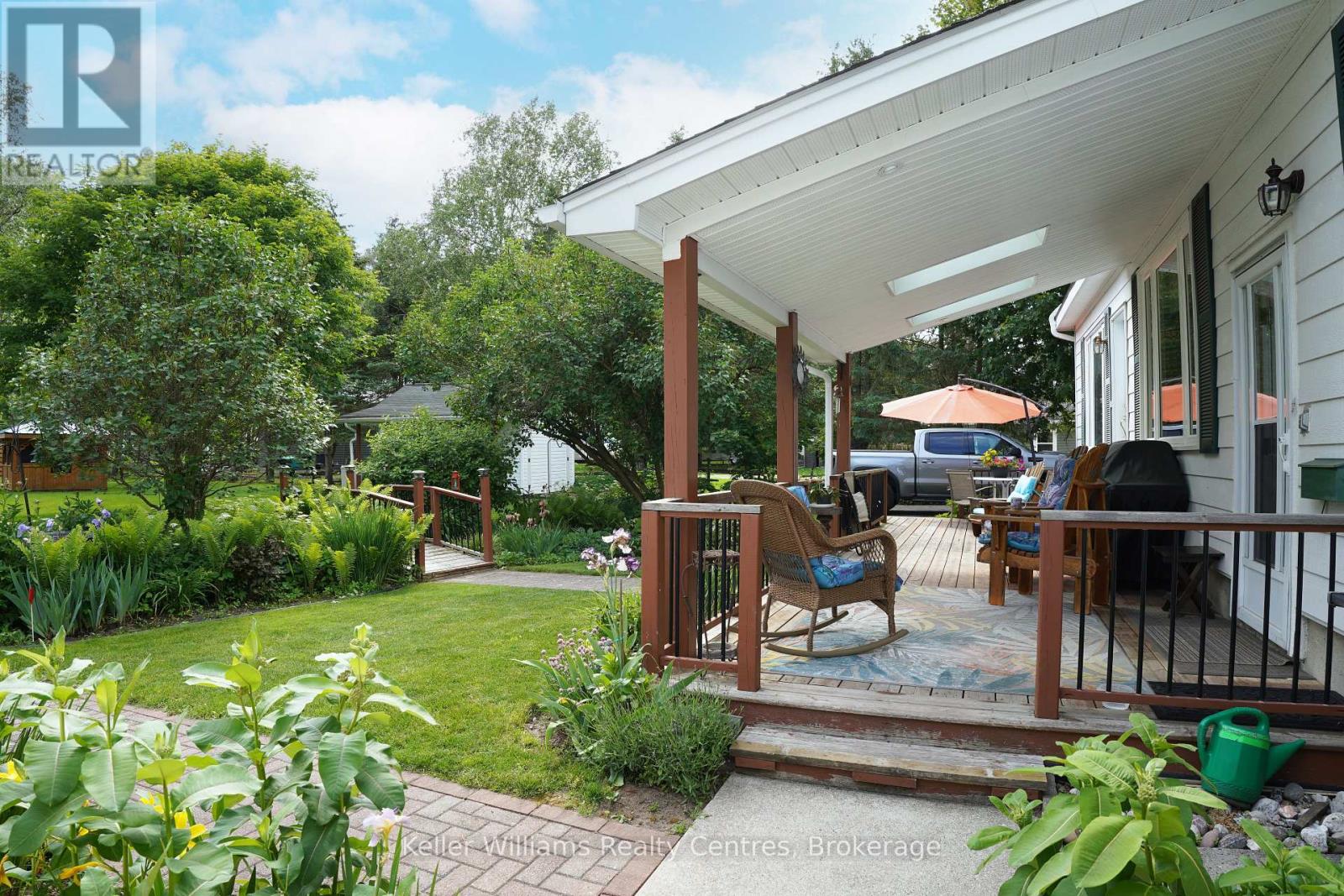 Covered back porch with patio furniture overlooking the lawn and gardens