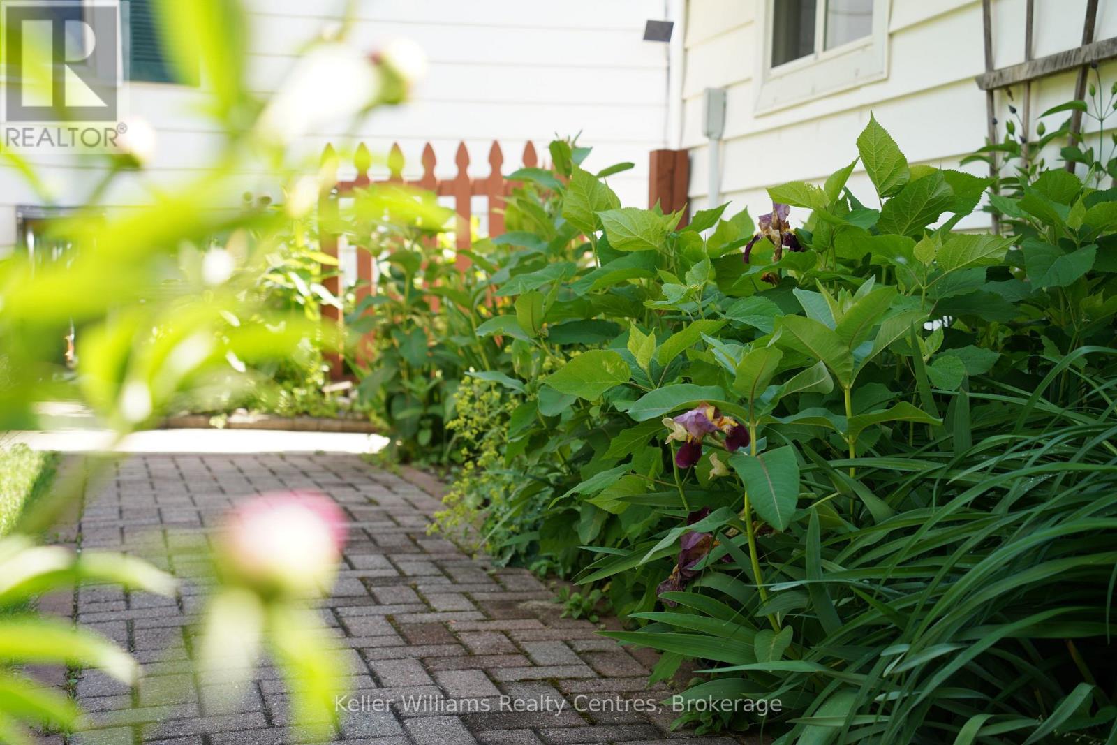 Herringbone paver path winding through restored perennial garden beds