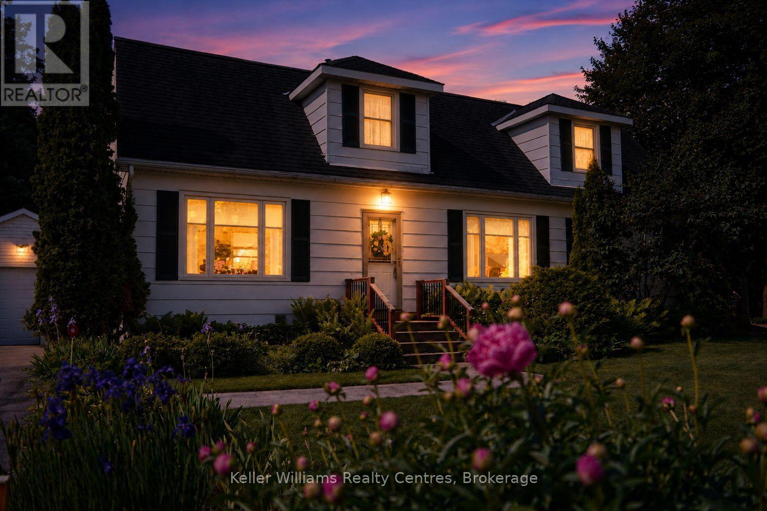 880 16th Street W at dusk — front porch glowing against restored perennial gardens